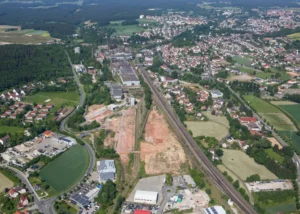 Luftaufnahme zeigt das ehemalige Maxhütten-Gelände in Sulzbach-Rosenberg während der Sanierung mit freigelegten Flächen, umgeben von Wohngebieten, Waldgebieten und Eisenbahnstrecke